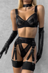Person wearing a black lingerie set with suspenders against a gray background